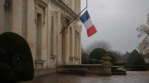 Illustration générée par IA d'un drapeau français en berne sur la façade d'une mairie, sous un ciel gris d'automne