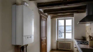 Illustration générée par IA d'une chaudière murale à gaz dans une cuisine de maison ancienne, en hiver, avec une fenêtre enneigée en arrière-plan